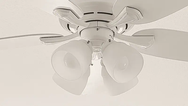 A white five-blade ceiling fan with a four-light kit, installed on a ceiling